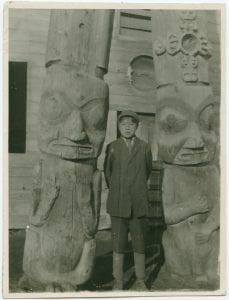 Boy with totem poles at Kispiox