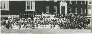 Large group of Indigenous children and youth are posed for a class photograph in front of Alberni Residential School building.