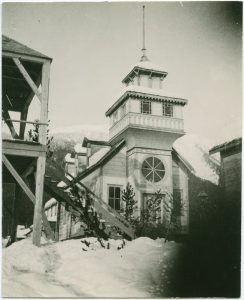 View of building with large circular window in the front in the winter time. Adjacent building has stairs leading towards the building.